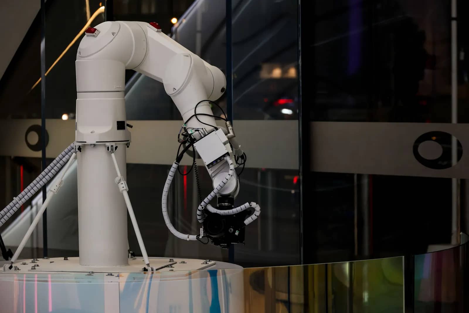 A white robotic arm at work in a modern glass-walled facility.